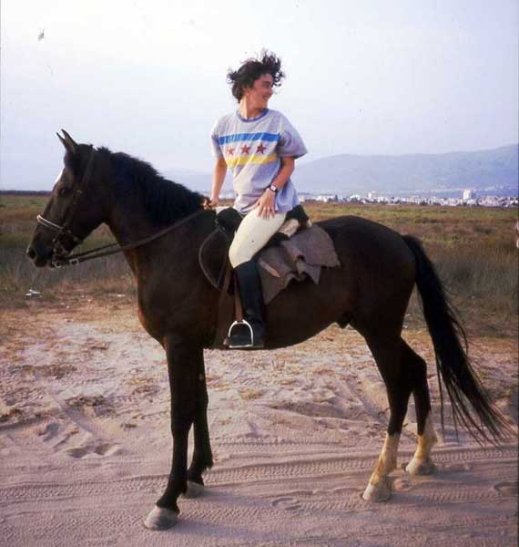 Italian woman riding a dark bay horse in the country side