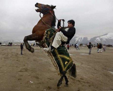 A middle eastern man rides his horse into a rear while pulling violently on the reins.
