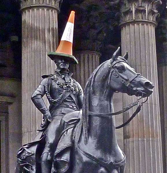 Statue of horse and rider with a 'dunce' traffic cone on his head