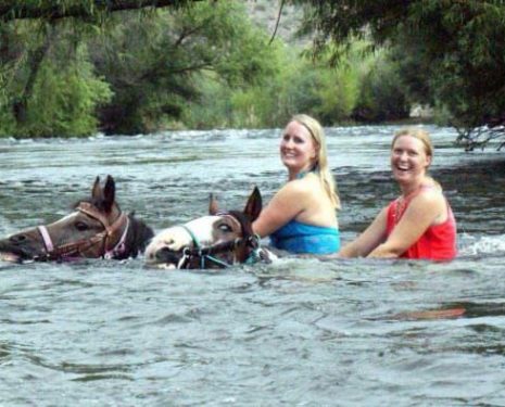 Young riders swimming their horses in water that is too deep.